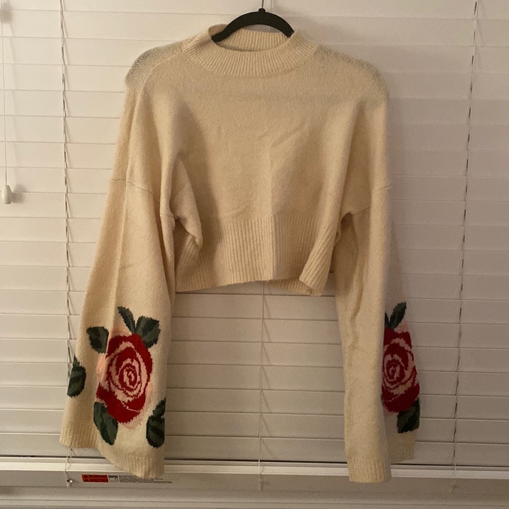 Cropped cream sweater with large flower detail.